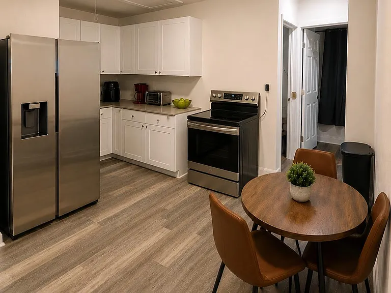 Efficient eat-in kitchen with stainless appliances, ample white cabinetry, and a compact dining area for two.