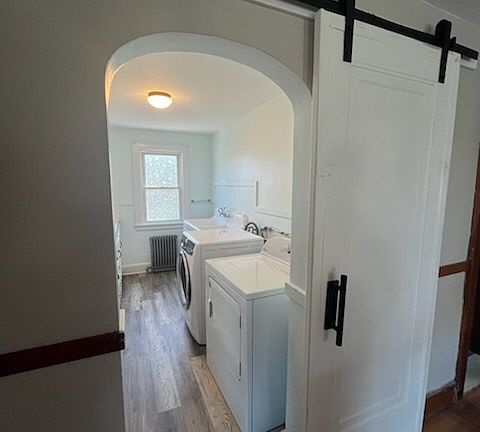 Laundry room / pantry entrance with sliding barn door, and arched doorway.