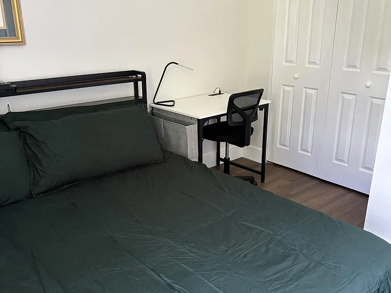 Furnished bedroom with King-size bed, dedicated desk workspace, and double-door closet for convenient storage.