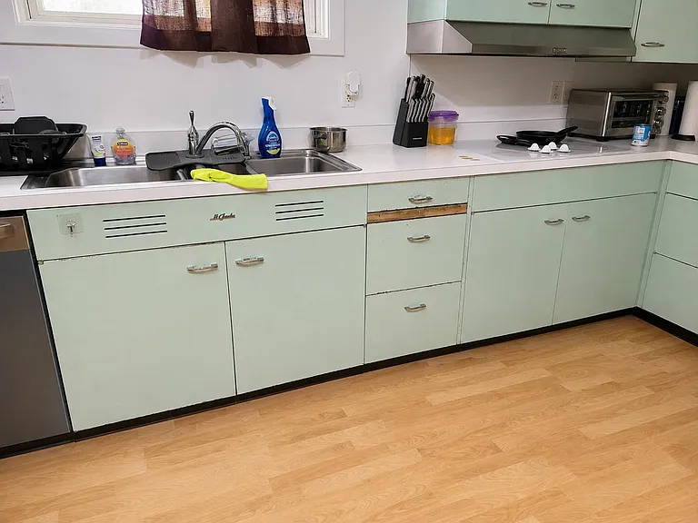 Functional kitchen workspace with ample cabinetry, long countertops, double sink, and a range hood for everyday cooking.