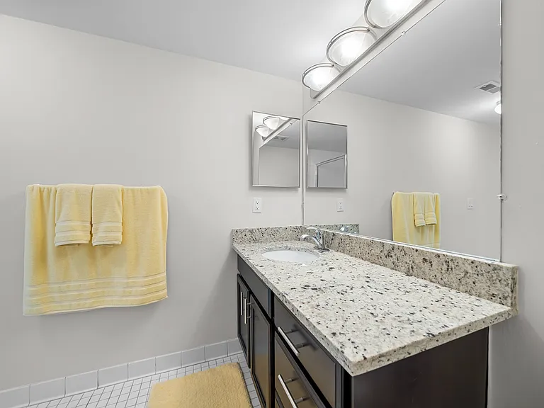 Modern bathroom with large vanity mirror and tub/shower at Lakeside Village Apartments in Clinton Township, MI