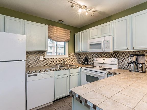 Efficient and full of storage, the kitchen features tile countertops, tile flooring, and an eye-catching backsplash.