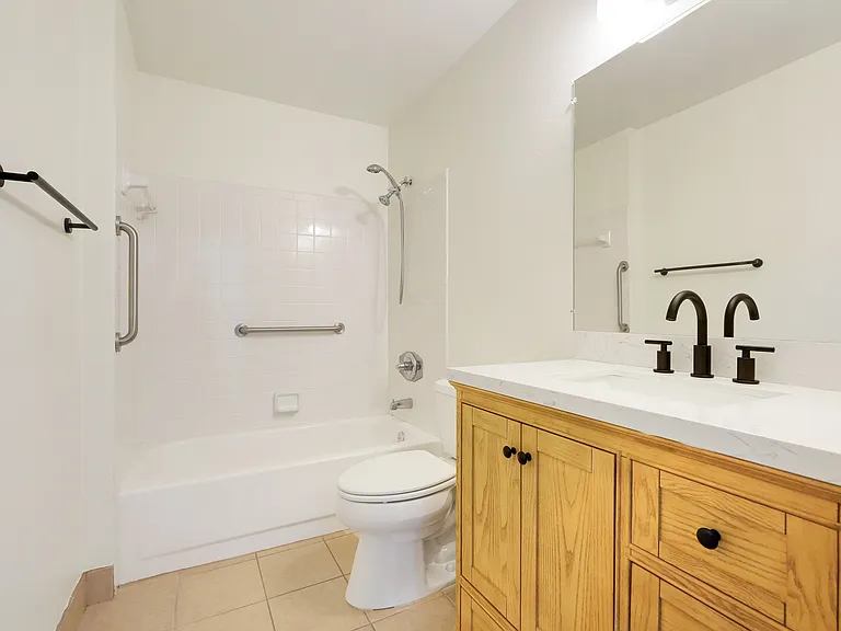 Conveniently located guest bathroom with a granite countertop vanity and shower-tub combo, perfectly positioned between the primary suite and guest bedroom.