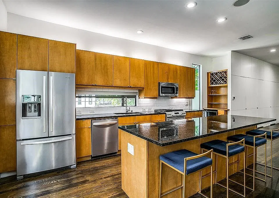 Bright spacious kitchen with large island, wine fridge, and stainless steel appliances