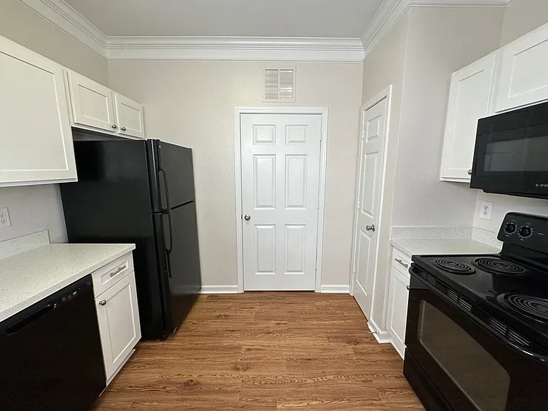 Contemporary kitchen with sleek black appliances, white cabinetry, quartz countertops, and wood-style flooring for a modern touch. Contemporary kitchen with sleek black appliances, white cabinetry, quartz countertops, and wood-style flooring for a modern