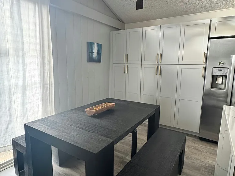 Dining area with picnic-style dining table and lots of pantry cabinets.