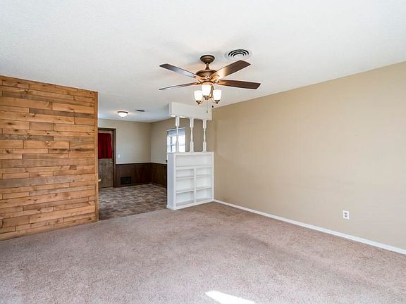 Another view of large living area with ceiling fan and built-ins!