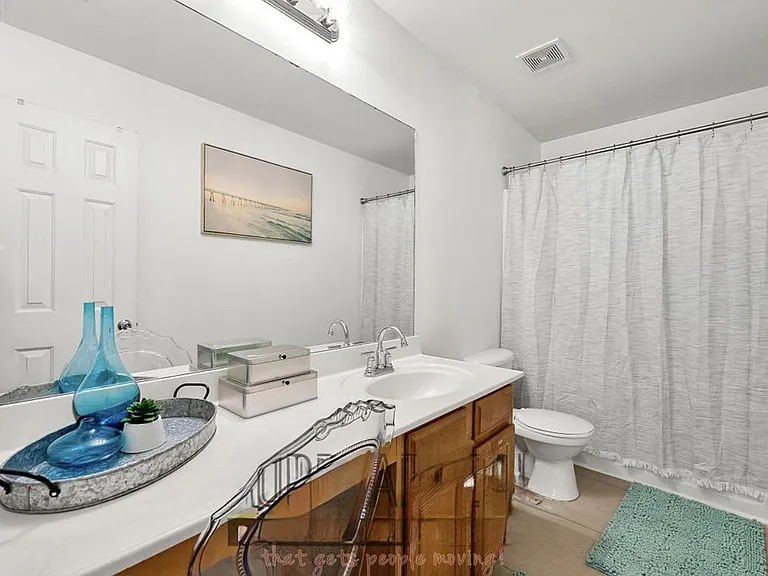 Full bathroom with wide vanity and large mirror, ample counter space, and a tub/shower combo with curtain.