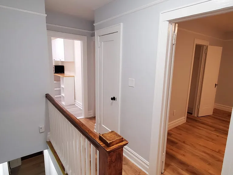 View from the top of the entry stairs down the main hall. On the right is the bedroom. The door in the middle lead to the upstairs bedroom/office. The light opening is the kitchen. The front room is to the right of the kitchen door. On the left are t