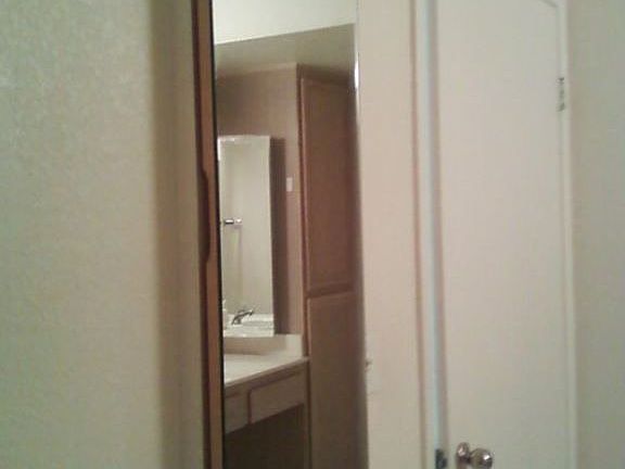 Mirror on wall concealing ironing board