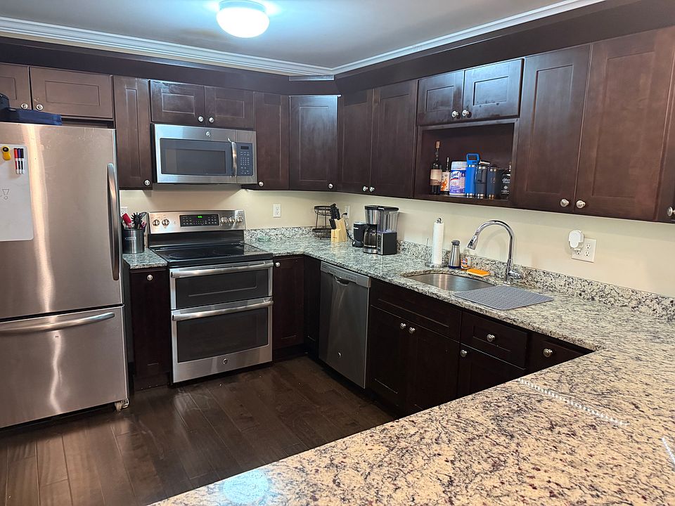Kitchen with double ovens, modern appliances, hardwood cabinets, and hanging light fixtures