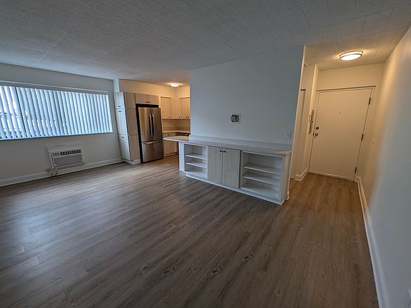 View from bedroom hallway across living room toward kitchen showing apartment entry