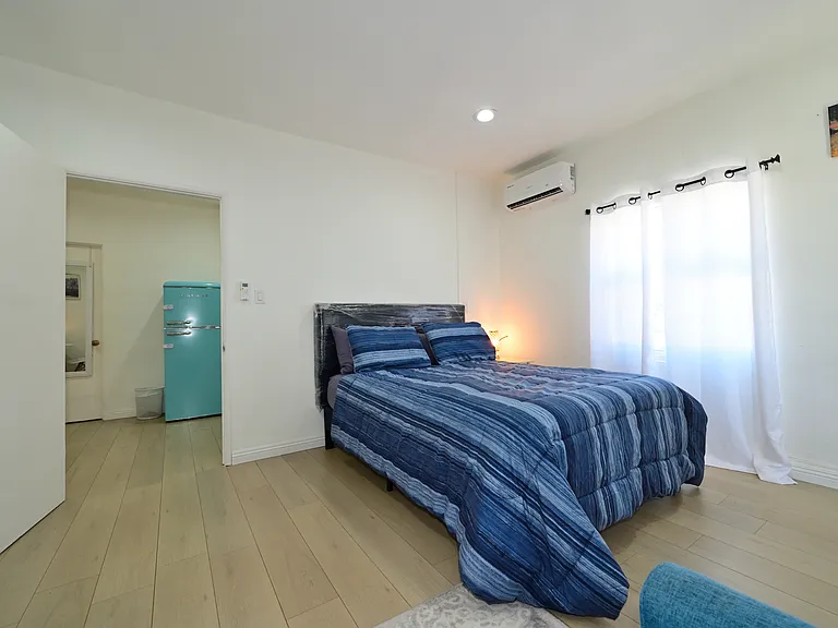 Super spacious bedroom furnished with TV, queen bed and mattress, mini split AC, Loveseat and Coffee table - with views of PCC