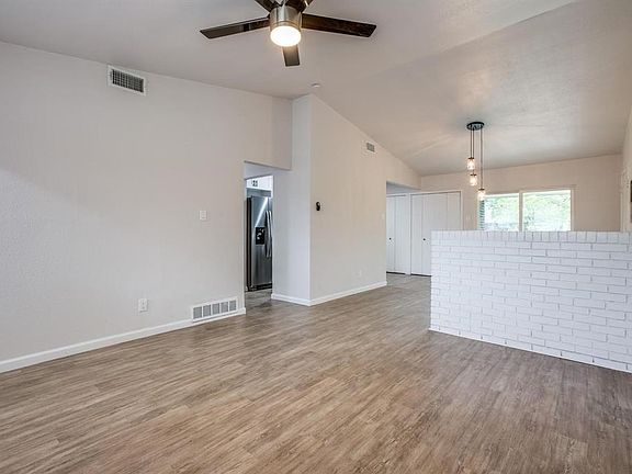 Unfurnished living room with vaulted ceiling, wood finished floors, and ceiling fan