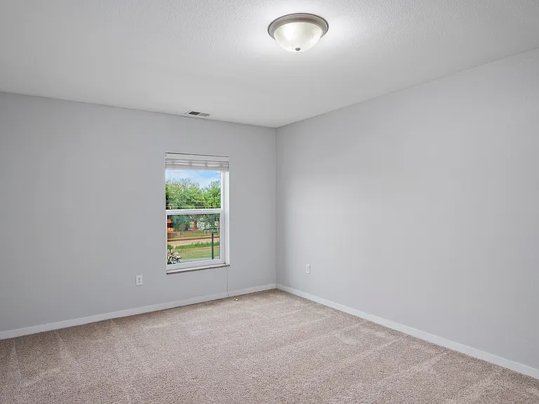 Bright, empty room with soft carpet and a large window offering natural light, perfect for a cozy bedroom setup. Bright, empty room with soft carpet and a large window offering natural light, perfect for a cozy bedroom setup.