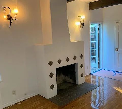 Cozy and charming fireplace framed by silver tiling. The beautiful wood beams are from 1928 and the hardwood floor is still gorgeous!