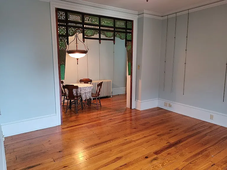 Main living area space with handcrafted cut wooden room divider with curtain rod behind to section off bedroom