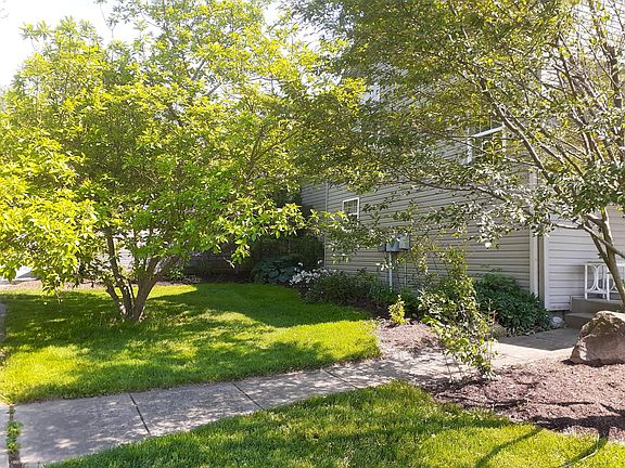 Perennials/flowering tree side yard. Two car car port behind pine tree. Six car shared spaces on other side of driveway.