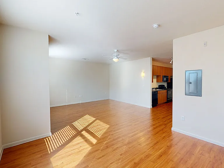 Apartment kitchen, dining and living room with wood-style flooring.