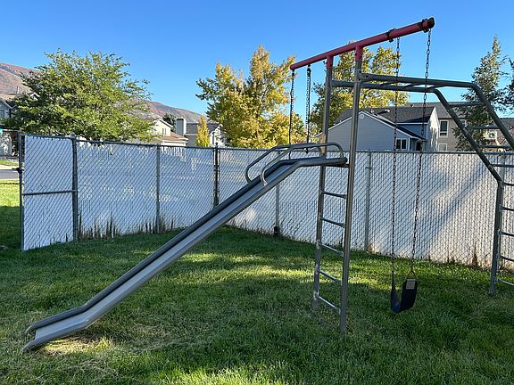 Fenced backyard with slide and swing playground