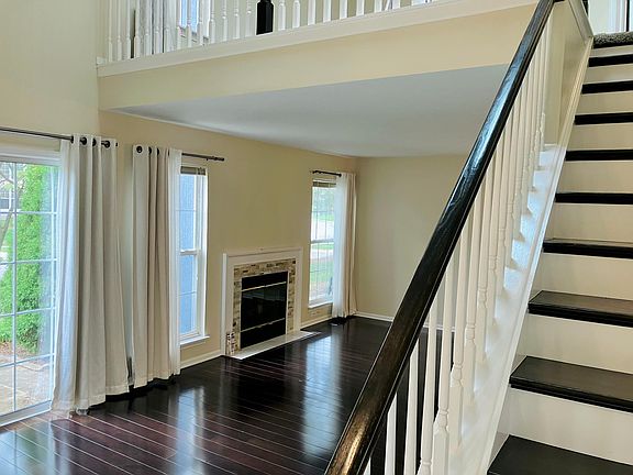 Well lit large living area with hardwood floors and cozy fireplace