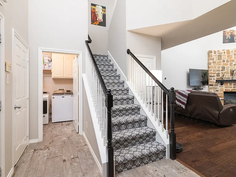 Welcoming entryway with a staircase leading to the second floor. Easy access to the laundry room and a cozy living area with fireplace and TV just steps away.