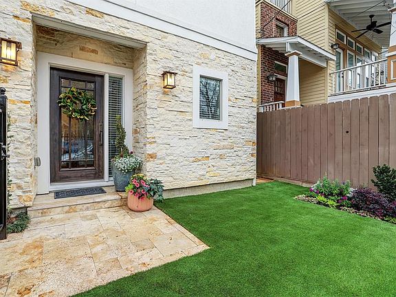 Front yard is enclosed with a wrought-iron fence & gate and was recently landscaped with artificial turf.