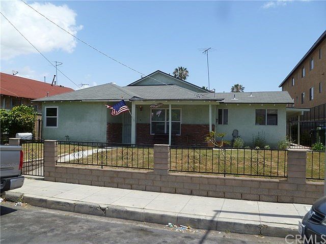 Front view of home, block/rod iron walls surround property.
