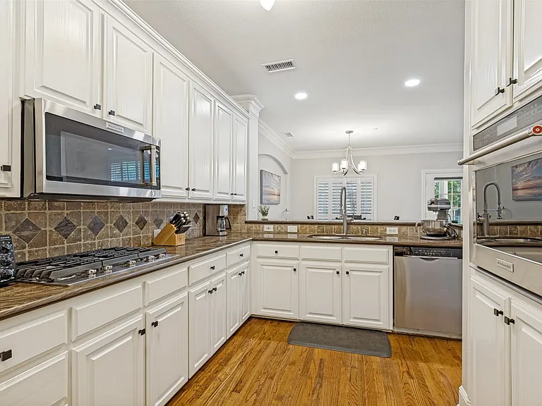 Kitchen featuring white cabinetry, stainless steel appliances, a tiled backsplash, wood-finish flooring, and recessed lighting