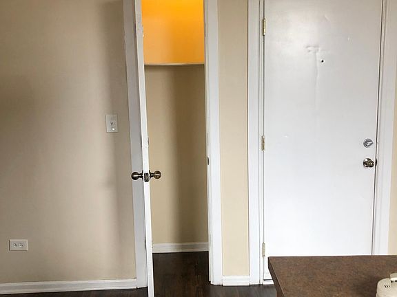 Coat/utility closet with light off kitchen and adjacent to front door