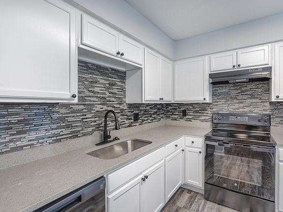 Modern kitchen with white cabinetry, backsplash, and black appliances