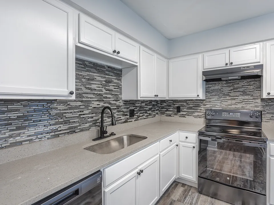 Modern kitchen with white cabinetry, backsplash, and black appliances