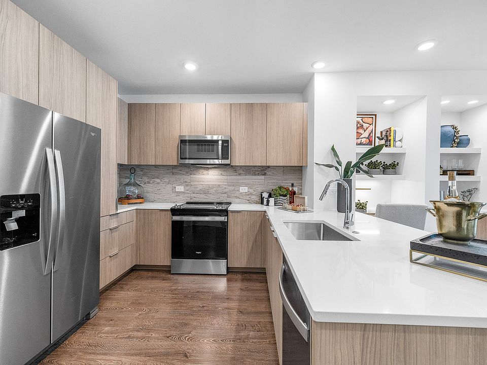 Modern kitchen with sleek appliances, elegant wood cabinetry, and a spacious white countertop with accent decor.