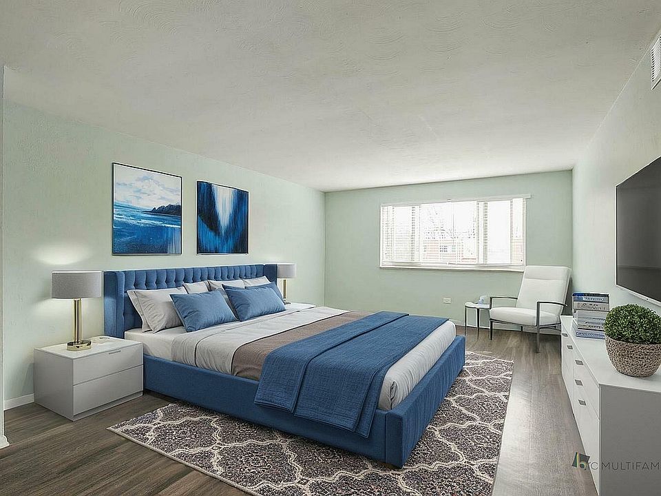 Elegant bedroom with a plush blue bed, modern decor, large window, and stylish artwork creating a serene atmosphere.