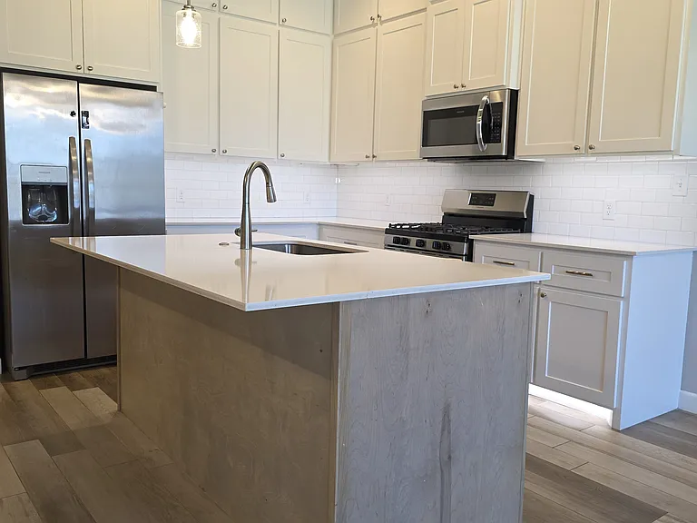 Single basin stainless steel sink with diswasher, trash bin, & seated island with pendant lighting