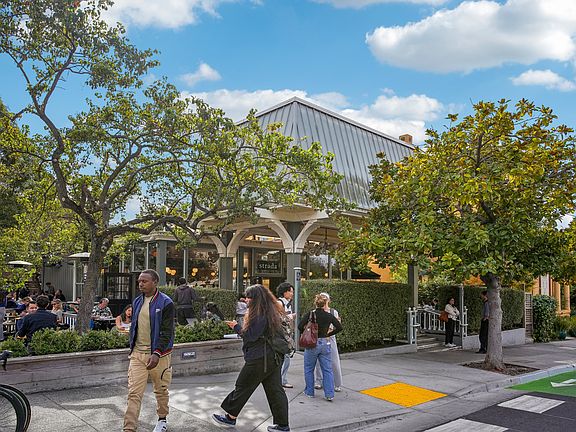 Lively street with group of people walking on the sidewalk in front of a building with a green awning