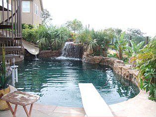 Tommy Bahama style  Black bottom pebble tech pool with grotto, waterslide