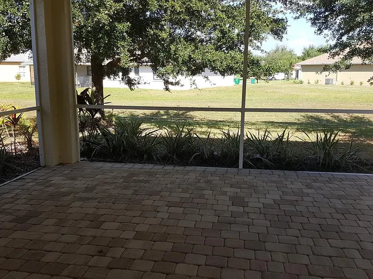 Screened in porch with pavers and landscaped view