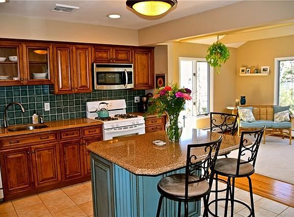 Renovated kitchen, featuring custom cabinetry, granite counters, newer appliances, new lighting and open floor plan as it flows 