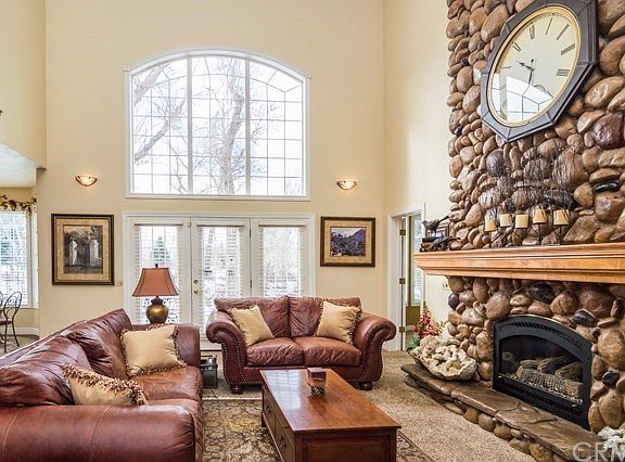Formal living room w/soaring high vaulted ceilings, beautifully large arched window & a floor-to-ceiling rock fireplace.