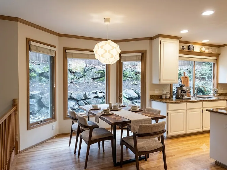 Sunny breakfast nook featuring hardwood floors, a modern pendant light, and expansive windows overlooking a private rockery and garden (computer staged)