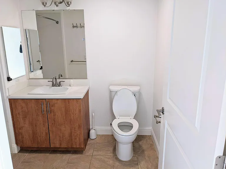 Hallway bathroom with water-saving toilet, vanity and storage.
