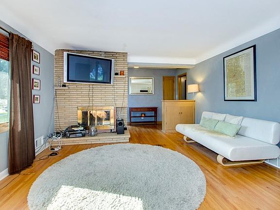 Spacious living room with brick fireplace, cove ceilings and exposed hardwood floors!