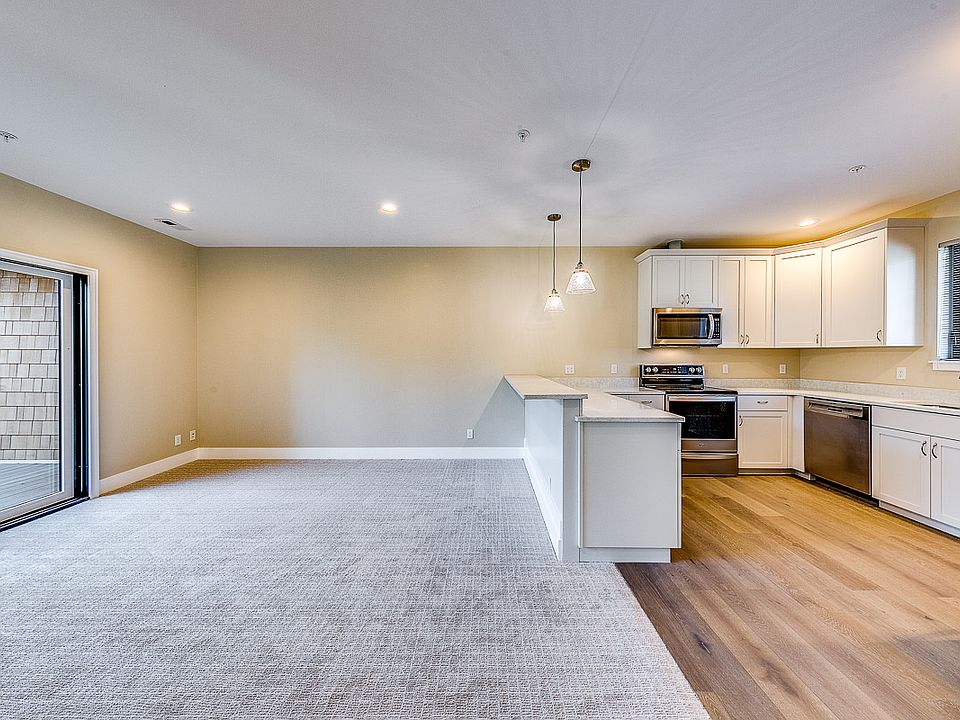 Bright kitchen with quartz counters, stainless appliances, breakfast bar, window facing west and large deck looking east over the ravine
