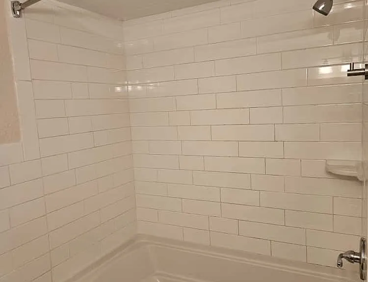 Large tub with tile surround and a fixed curved shower rod.