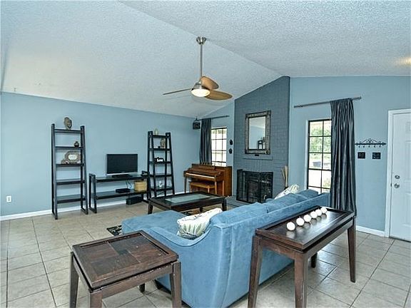 Large living room with fireplace, pitched ceiling, and large windows to let in a lot of natural light