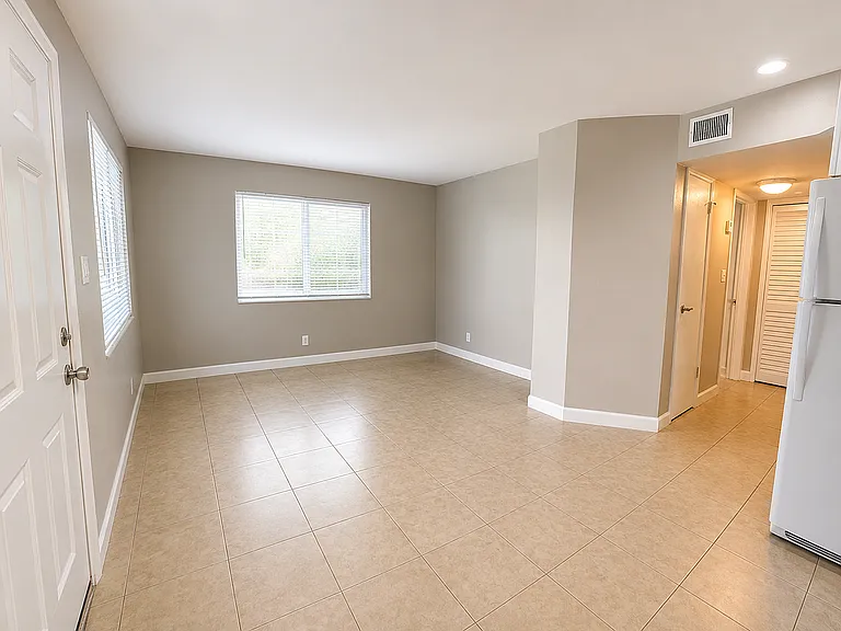 Bright and spacious living area with large windows, elegant tile flooring, and modern recessed lighting, ideal for cozy living.