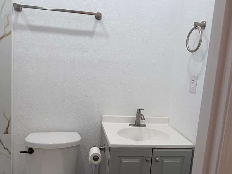 Full bath with a vanity sink, toilet, and convenient towel and ring holders for everyday use.