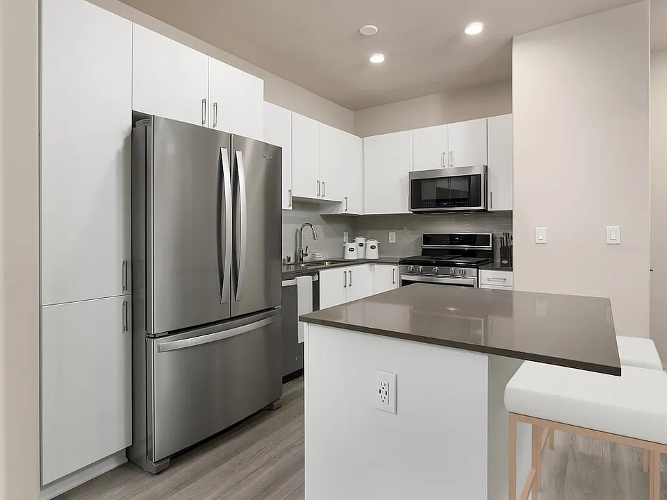 Renovated Package I kitchen with quartz countertops, white cabinetry, stainless steel appliances, hard surface vinyl plank flooring, and tile backsplash