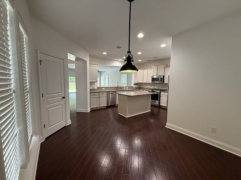 Bright dining space situated perfectly right off the main kitchen island. Highlights crisp white trim, elegant window blinds for natural light control, and premium recessed ceiling lights."